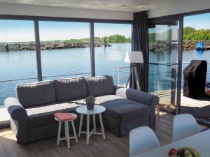 een woonkamer met een bank en uitzicht op het water bij WELL Hausboote in Boltenhagen