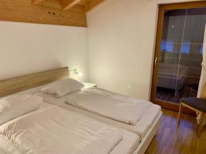 um quarto com 2 camas brancas e uma janela em Feriendorf Via Claudia Ferienhaus Martin em Lechbruck