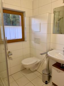 uma casa de banho branca com um WC e um lavatório em Feriendorf Via Claudia Ferienhaus Martin em Lechbruck