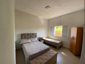 - une chambre avec un lit, un banc et une fenêtre dans l'établissement Rancho em Capitólio-MG, à Capitólio
