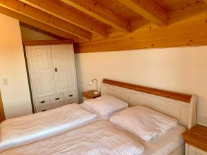 a bed in a bedroom with a wooden ceiling at Feriendorf Via Claudia Ferienhaus Lechsee in Lechbruck