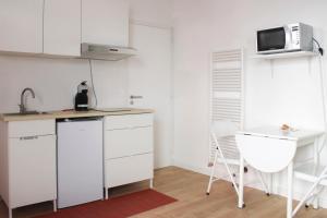 モントルイユにあるBeautiful renovated studio in dynamic neighborhoodのキッチン(白いキャビネット、テーブル、電子レンジ付)