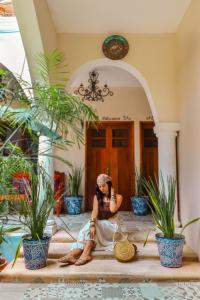 a woman sitting on the porch of a house at Le Muuch Hotel Boutique in Valladolid