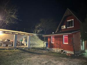 ein kleines rotes Haus mit einer Veranda in der Nacht in der Unterkunft Vikendica DUNAV Vinci in Golubac