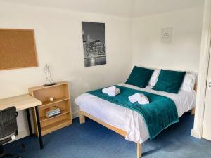 een slaapkamer met een bed met groene lakens en een bureau bij In Royal Leamington Spa 4 bed with free parking in Leamington Spa