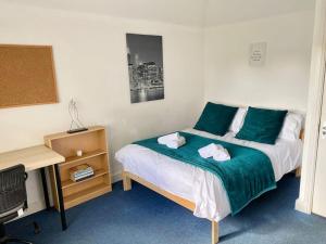 a bedroom with a bed with green sheets and a desk at In Royal Leamington Spa 4 bed with free parking in Leamington Spa
