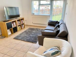 a living room with a couch and a flat screen tv at In Royal Leamington Spa 4 bed with free parking in Leamington Spa