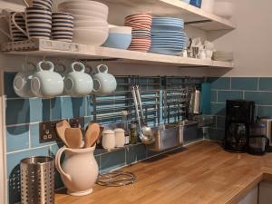 a kitchen with plates and utensils on shelves at Beach Front Coastal Retreat with Sea Views in Kingsbridge