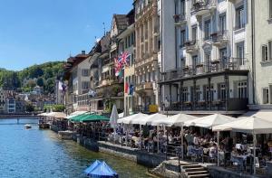 grupa ludzi siedzących przy stołach przy rzece w obiekcie Hotel Pickwick and Pub "the room with a view" w Lucernie