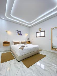 een witte slaapkamer met een groot bed en een raam bij Résidence America in Dakhla