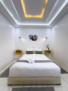 a bedroom with a large white bed and a ceiling at Résidence America in Dakhla