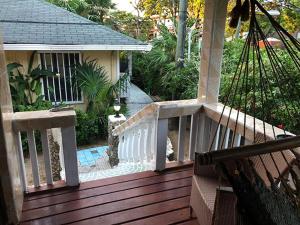 eine Holzterrasse mit einem weißen Geländer an einem Haus in der Unterkunft Coconut Tree West End in West End