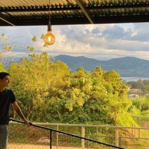 a man standing on a balcony looking out of a window at Cabinas Morpho Gardens in Nuevo Arenal