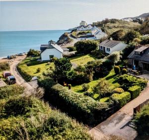 a house on a hill next to the ocean at Beach Front Coastal Retreat with Sea Views in Kingsbridge