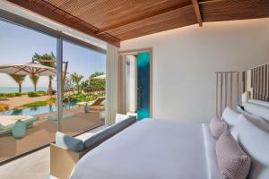 The St. Regis Red Sea Resort في Ḩanak: غرفة نوم مع سرير وإطلالة على المحيط
