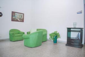 Sala de estar con 2 sillas verdes y TV en CASA HOTEL ALNOR, en Medellín