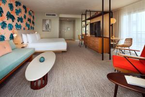 a hotel room with a bed and a couch and a tv at The Laylow, Autograph Collection in Honolulu