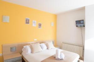 - une chambre avec un lit blanc et un mur jaune dans l'établissement Hostal-Casa Rural Rosa-Nonna, à Sigüenza