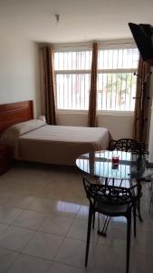 ein Schlafzimmer mit einem Bett und einem Tisch mit einem Glastisch von sidx in der Unterkunft Estúdio Vieira in Praia