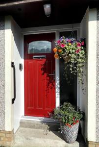 a red door with two potted plants in front of it at Cragside in Callander