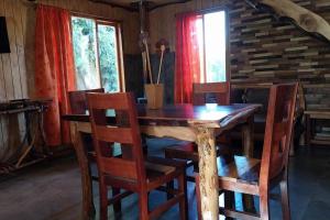 una mesa de madera y sillas en una habitación en Cabaña El artesano Puyehue en Ñilque