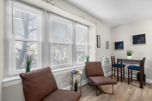 a living room with two chairs and a table and windows at Cozy City View Apartment in Philadelphia