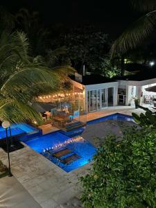 a swimming pool at night with a house at Pousada Village Cozumel in Guarujá