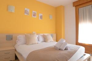 - une chambre avec des murs jaunes et un lit avec des oreillers blancs dans l'établissement Hostal-Casa Rural Rosa-Nonna, à Sigüenza