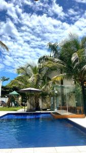 a large blue swimming pool with palm trees next to a house at Pousada Village Cozumel in Guarujá