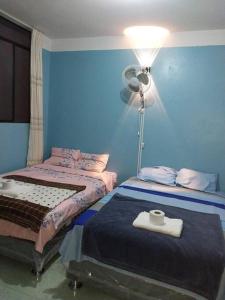 Habitación azul con 2 camas y ventilador. en Hospedaje EDUCOL en Moyobamba