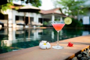 a drink sitting on a table next to a swimming pool at Damnak Soksan Hotel in Siem Reap