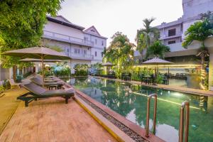 a pool with chairs and umbrellas next to a building at Damnak Soksan Hotel in Siem Reap