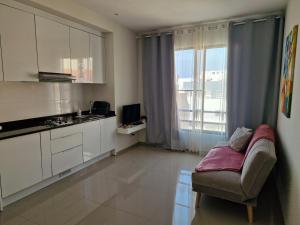 a kitchen with white cabinets and a chair in a room at Apartamentos Beira-Mar in Mindelo