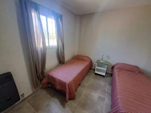 two beds in a room with a window at Complejo Pino Azul in General Roca