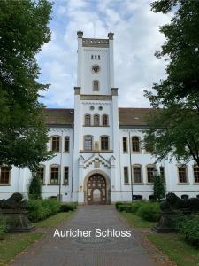 un gran edificio blanco con una torre de reloj en Eschen´s Allee, en Aurich