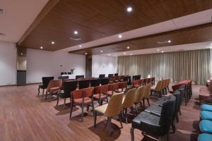 uma sala de conferências com cadeiras, uma mesa e um pódio em Palette - Hotel Royal Palace Morbi em Morbi