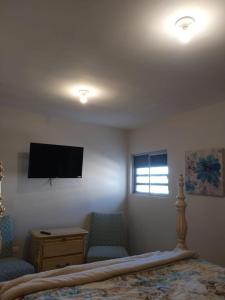 a bedroom with a bed and two chairs and a tv at Alojamiento Entero en Azores Residencial in Hermosillo