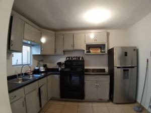 a kitchen with white cabinets and a black refrigerator at Alojamiento Entero en Azores Residencial in Hermosillo