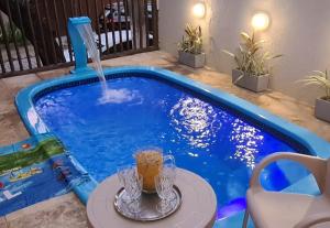 a drink sitting on a table next to a swimming pool at Pousada e Hostel Casarão 2030 in Natal