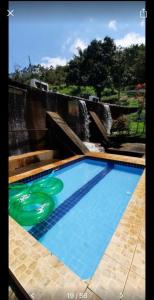Apt quarto 228 - hotel pedra Rodeadouro-Bonito-PE في بونيتو: حمام سباحة مع اثنين من الأطباق الطائرة أمام الشلال
