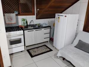 a kitchen with a stove and a white refrigerator at Flat Theobald in Três Coroas