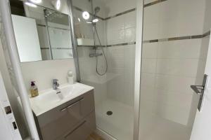 een witte badkamer met douche en wastafel bij Nice studio near the sea in Arcachon