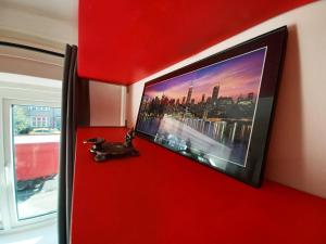 a red wall with a flat screen tv on it at The Gemstone Manor in Watford