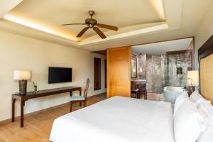 Schlafzimmer mit einem Bett, einem Schreibtisch und einem TV in der Unterkunft Centara Grand Beach Resort Phuket - SHA Plus in Karon Beach
