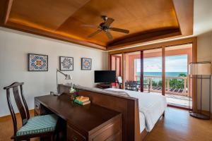 a bedroom with a desk and a bed with a view at Centara Grand Beach Resort Phuket in Karon Beach
