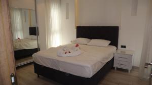 a bedroom with a bed with white sheets and a mirror at Villa Dream Kuşadası Pool- Garage in Kuşadası