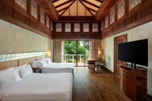 a bedroom with two beds and a flat screen tv at Centara Grand Beach Resort Phuket - SHA Plus in Karon Beach