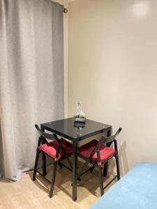 a black table with two red chairs next to a bed at Cosy Studio Flat in London