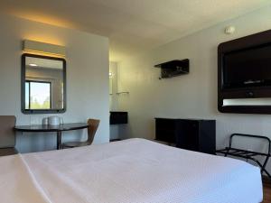 a bedroom with a bed and a table and a television at Motel 6-Simi Valley, CA in Simi Valley