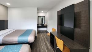 Motel 6-Galveston, TX في جالفيستون: غرفة فندقية بسرير وتلفزيون بشاشة مسطحة